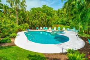 a swimming pool in a yard with chairs and trees at Conch-Captiva Beach Villas in Captiva