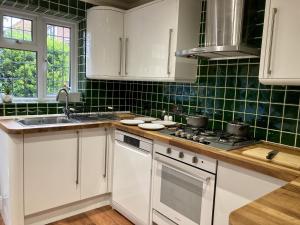 a kitchen with white cabinets and green tiles at Brackens in Brentwood