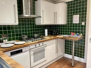 a kitchen with green tiled walls and white cabinets at Brackens in Brentwood