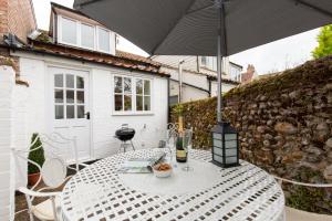 a white table with an umbrella on a patio at April Cottage in East Rudham
