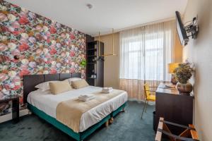 1 dormitorio con 1 cama con pared de flores en Ama Hôtel, en Biarritz