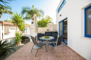 eine Terrasse mit einem Tisch und Stühlen vor einem Haus in der Unterkunft Flouressia Gardens in Protaras