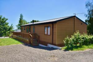 a small wooden house with a porch and a yard at Rowan a welcoming countryside lodge in Ryde