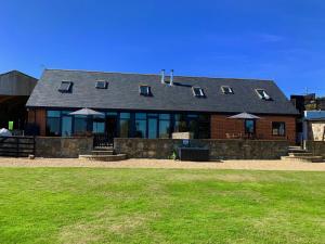 a brick building with windows and a grass field at Tithe Barn a Stunning family home with panoramic views in Ryde