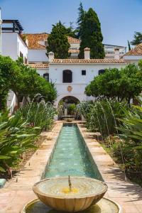 un jardín con una fuente frente a un edificio en Luxury stay near Puente Romano, always Heated Pool 5*, en Marbella
