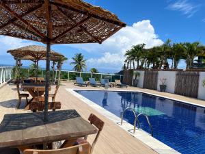 a patio with a table and umbrella next to a swimming pool at Chalés Alto dos Milagres in São Miguel dos Milagres