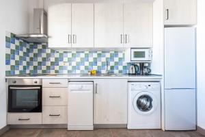 a kitchen with white cabinets and a washer and dryer at Apartamento Atalaya Golf I-II-III in Estepona