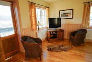 a living room with two chairs and a flat screen tv at Eyjar Fishing Lodge in Breiðdalsvík