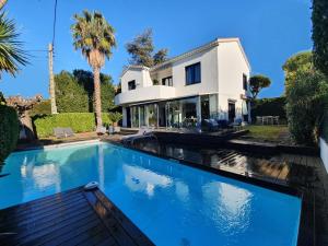 a swimming pool in front of a house at VILLA BEL AIR CANNES - 240m2 - Freshly completely renovated - Beach - Pool - No Party allowed - No bachelor-ette stay - 25 mn walk from beach and Palais des festivals in Cannes