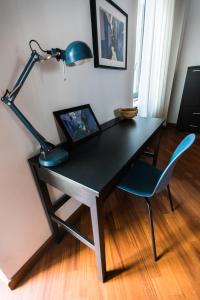 a desk with a blue lamp and a chair at Orpheus Apartment in Turin