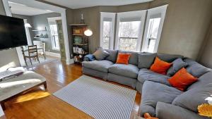 a living room with a gray couch and orange pillows at Linden Hills Luxury Charmer in Minneapolis