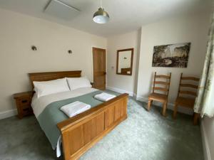 a bedroom with a large bed and a chair at Willow Cottage in Longney