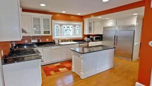 uma grande cozinha com armários brancos e electrodomésticos de aço inoxidável em Linden Hills Luxury Charmer em Minneapolis