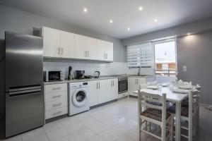 uma cozinha com armários brancos, uma mesa e uma máquina de lavar louça em Pelagia apartments in Ilha de Rhodes