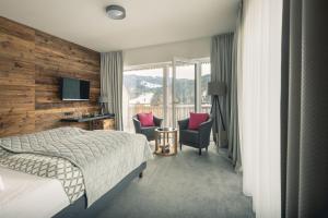 a hotel room with a bed and two chairs at Torghele's Wald & Fluh in Balderschwang