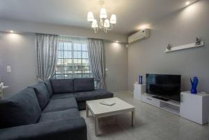 a living room with a blue couch and a tv at Pelagias apartments in Rhodes Town