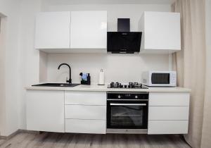 a kitchen with white cabinets and a microwave and a stove at CooZee Apartment in Alba Iulia