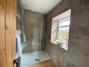 a bathroom with a shower with a tub and a sink at Willow Cottage in Longney