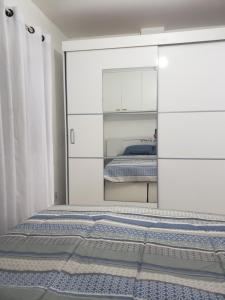 een slaapkamer met een bed en een witte kast bij Loft encantador próximo a Roda Gigante,excelente localização com ar condicionado in Balneário Camboriú
