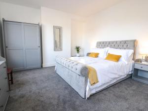 a bedroom with a large bed with white sheets and orange pillows at Anandom in Blackpool