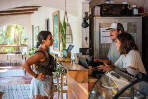 a man and two women standing at a cash register at Believe Surf & Yoga Lodge Santa Teresa in Santa Teresa Beach
