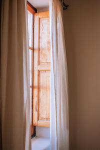 una ventana abierta con una cortina delante en Posada Finca Garciarena en Agrelo