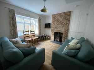 a living room with two blue couches and a fireplace at Willow Cottage in Longney