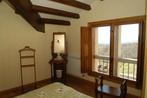 a room with a bed and two windows and a table at Alojamiento Rural El atardecer de Sanabria in San Juan de la Cuesta