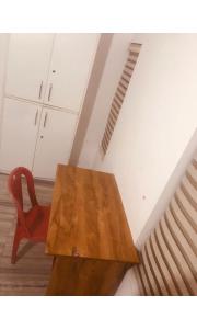 a wooden table and a red chair in a room at Redbell Inn Airport Hotel in Kondotti