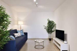 uma sala de estar com um sofá azul e uma televisão em Cosy and Modern Apartment Portu Frailis em Àrbatax