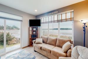 a living room with a couch and a tv at Sunset Beach House in Coos Bay