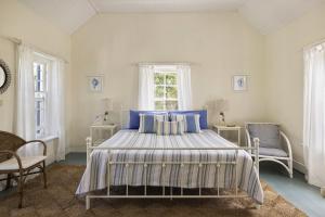 a bedroom with a bed and two chairs and a window at Tamarind home in Governorʼs Harbour