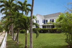 una casa blanca con palmeras delante en Tamarind home en Governor's Harbour