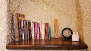 een plank met boeken en een spiegel en een muur bij Adelya Cave Hotel Apartments in Goreme