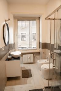 La salle de bains est pourvue de 2 lavabos et d'une douche en verre. dans l'établissement Bubi House Porta Venezia, à Milan