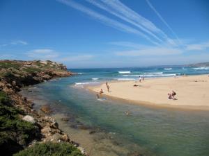 a group of people on a beach near the water at O Refúgio dos Pais in Bordeira