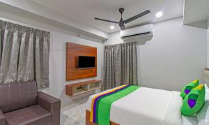 a bedroom with a bed and a tv and a chair at Treebo Trend Abhi Suites, Guntur in Guntūr