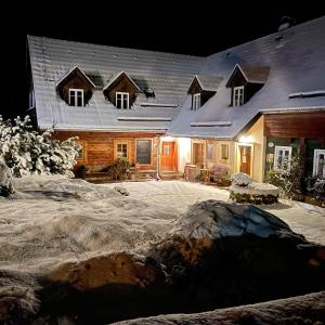 duży drewniany dom ze śniegiem w obiekcie Penzion Na Stodolci w mieście Chřibská