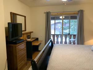 a bedroom with a bed and a television and a balcony at Telemark #4 Townhouse On The River in Red River