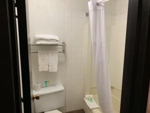 a bathroom with a toilet and a shower with towels at King's Inn in Torrington