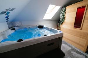 Habitación con bañera grande con agua azul. en Wellness & Spa Loft Studio apartman Lentulis, 