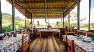 Casita Rivera Río Celeste في بيجاغوا: غرفة طعام بها طاولات وكراسي ونوافذ كبيرة