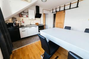 une cuisine avec une table blanche et des appareils noirs dans l'établissement Wellness & Spa Loft Studio apartman Lentulis, 