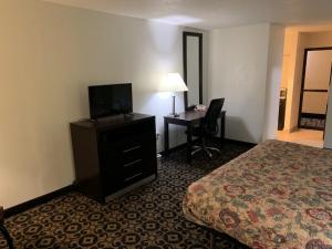 a hotel room with a bedroom with a bed and a desk at King's Inn in Torrington