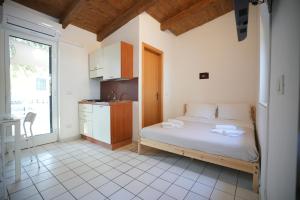 a bedroom with a bed and a kitchen with a window at Keys of Sicily - Bungalows sul mare in Marina di Modica