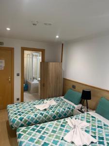 two beds in a hotel room with towels on them at Hostal Restaurante in Pamplona