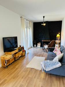 sala de estar con sofá azul y TV de pantalla plana en Ca la Carme, en Santa Pau
