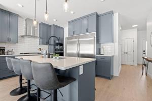 a kitchen with blue cabinets and a kitchen island with bar stools at Family Home Retreat - 9 mins to WEM - Vintage Arcade-Ping Pong -Air Conditioning in Edmonton