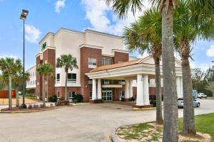 un hotel con palmeras frente a un edificio en Holiday Inn Express Hotel & Suites Lucedale, an IHG Hotel, en Lucedale