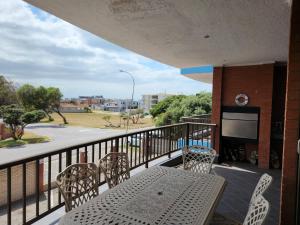 a patio with a table and chairs on a balcony at De Reyge in Jeffreys Bay